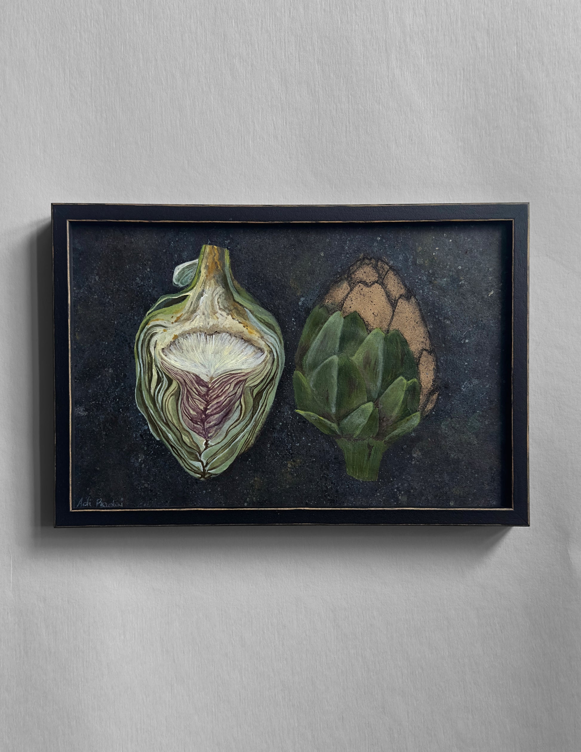 Framed artwork of two artichokes on a dark background. By Adi Radai