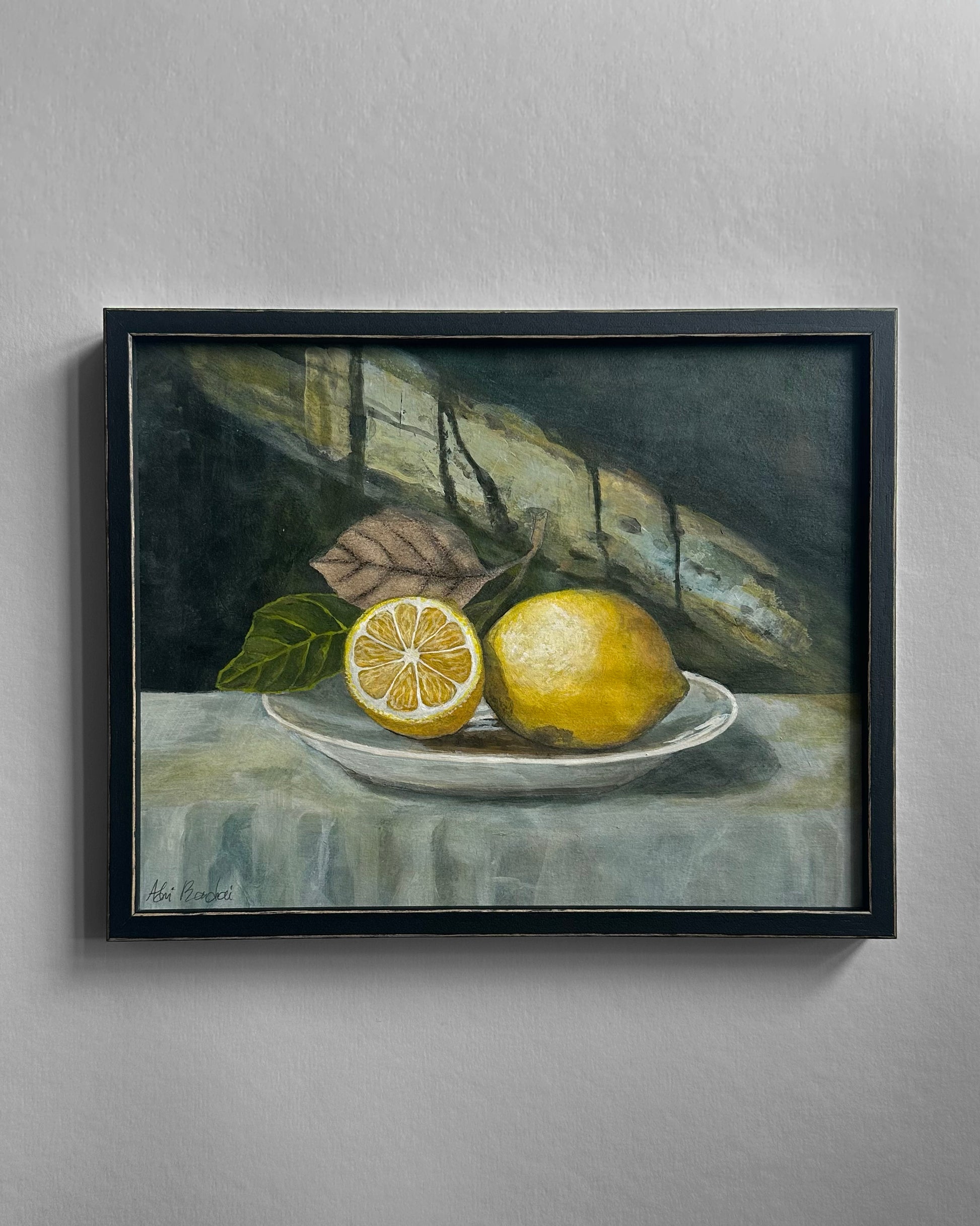 Framed still life painting of lemons on a plate with leaves.
