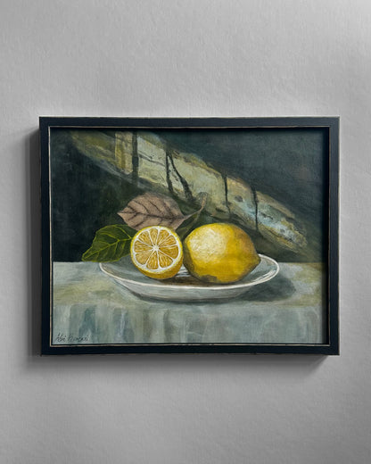 Framed still life painting of lemons on a plate with leaves.